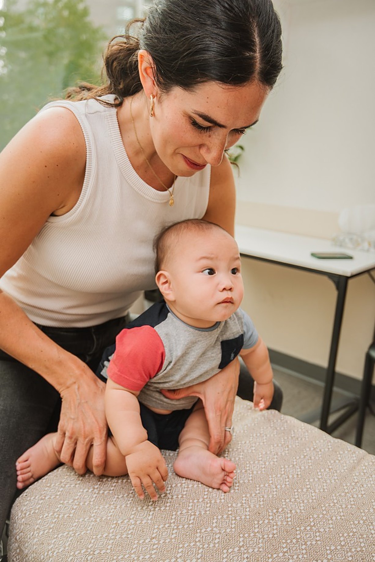 A Baseline practitioner supporting an infant seated on a treatment table